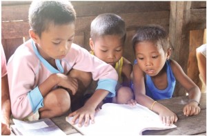 (L) Aldimar shows his book to his younger brothrs Jamar and Junimar. Under the care of their grandmother, these three children get enrolled in school through the Pantawid Pamilyang Pilipino Program.