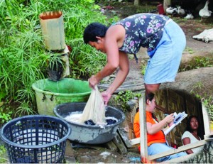 Scarcity of water supply makes it difficult for this woman to wash their cloths. (Inset) Regional Field Coordinator of the National Household Targeting System for Poverty Reduction (NHTS-PR), Therese Margarette C. Babanto, interviews a TS Pablo victim in Barangay Nueva Era, Bunawan, Agusan del Sur and at the same time explains to her about NHTS-PR.