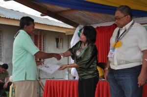BCNASA president Samuel Tabugod receives his certificate of occupancy which is personally handed by DSWD-XIII regional director Minda Brigoli, with Bislig City mayor Librado Navarro.