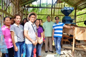 Roy Serdeña (in stripes) and Mayor Candelario Viola, Jr. (in green polo) stand beside corn mill equipment in Barangay Talisay, Hinatuan, Surigao del Sur. 